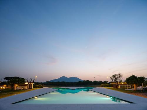 a swimming pool at dusk with mountains in the background at Secret Garden Resort & Spa in Palma Campania