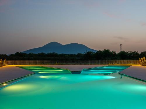 a group of blue swimming pools with mountains in the background at Secret Garden Resort & Spa in Palma Campania