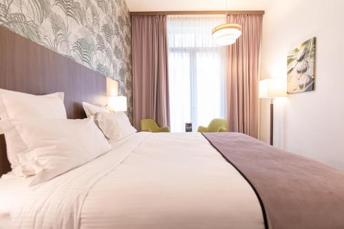 a large white bed in a hotel room at Quality Hotel Bordeaux Centre in Bordeaux