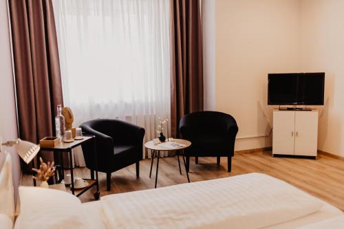 Pokój hotelowy z 2 krzesłami, stołem i telewizorem w obiekcie Fährhaus Kollmar w mieście Kollmar