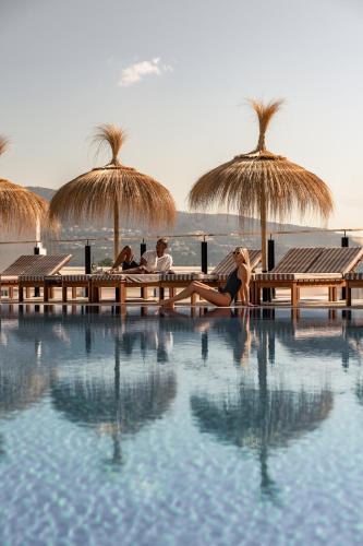 a group of people sitting around a pool with umbrellas at Cooks Club Calvia Beach - Adults Only in Magaluf