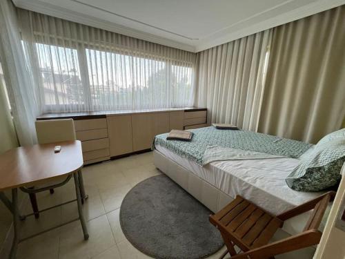 a bedroom with a bed and a desk and windows at ВИЛЛА 347 В ТЕКИРОВА 3+1 in Kemer