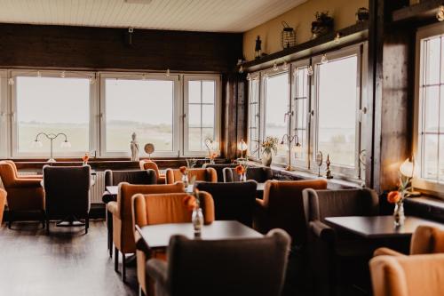 - une salle à manger avec des tables, des chaises et des fenêtres dans l'établissement Fährhaus Kollmar, à Kollmar