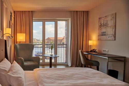 a hotel room with a bed and a desk and a window at Hotel am Delft in Emden