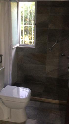 baño con aseo y ducha y ventana en Alborada Dayman, en Termas del Daymán