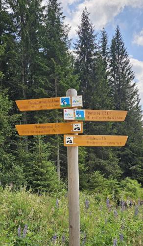 a wooden sign with several signs on a pole at Horská Kvilda - Ubytování U Chvalů in Horská Kvilda