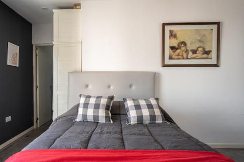 1 cama con 2 almohadas y una foto en la pared en Divino mono ambiente en el centro de Pinamar, cerca de todo en Pinamar