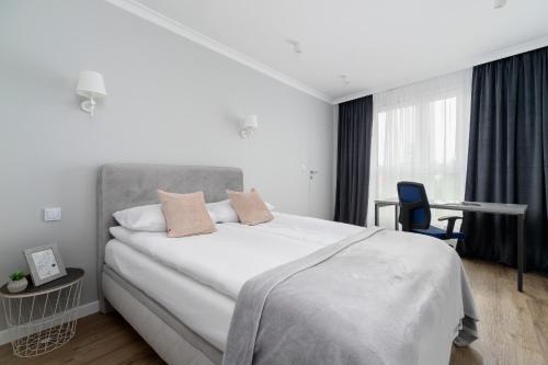 1 dormitorio con 1 cama blanca grande y escritorio en Modern Apartment suitable for Remote Work with Balcony & Parking by Renters, en Cracovia