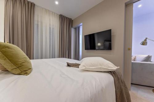 a bedroom with a white bed with pillows and a television at Luxury Villa Del Sogno with pool, jacuzzi, parking in Trogir