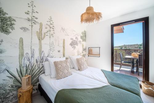 ein Schlafzimmer mit einem Bett und einem Wandbild von Kaktus in der Unterkunft L'Escale de Collioure - Climatisé, parking privé sécurisé, vue mer in Collioure