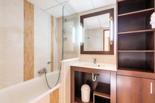une salle de bain avec un lavabo, une baignoire et un miroir dans l'établissement Residence Cap Hermes - maeva Home, à Fréjus