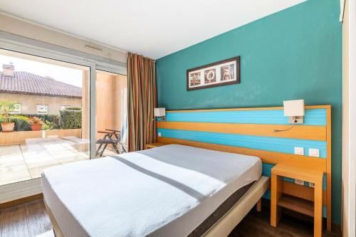 une chambre avec un lit avec un mur bleu dans l'établissement Residence Cap Hermes - maeva Home, à Fréjus