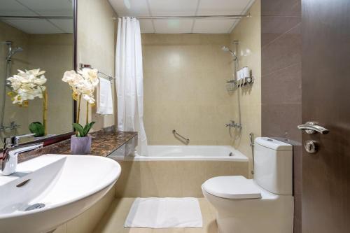 a bathroom with a toilet and a sink and a tub at GuestReady - Oasis paradise at Riah Tower in Dubai