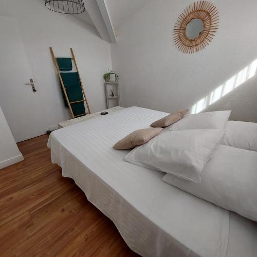 a bedroom with a white bed with pillows and a mirror at La Cas'Aline in La Saline les Bains