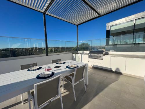 a kitchen with a white table and chairs and large windows at villagoldra rentals - Luxury and Family Villa in Goldra de Baixo