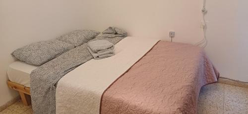 a bedroom with a bed with a blanket and pillows at Galilean villa with jacuzzi in Qiryat ‘Amal