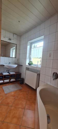 a bathroom with a tub and a sink and a window at Ferienhaus Paul in Neidenbach