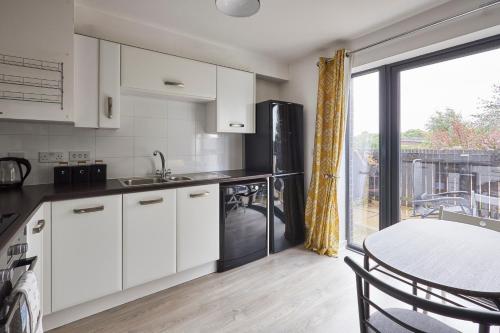 uma cozinha com armários brancos, uma mesa e uma janela em Host & Stay - London Avenue em Glasgow