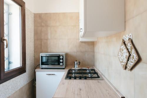 a kitchen with a stove and a microwave at Villetta L'Ajara - Salento - Ortelle in Ortelle