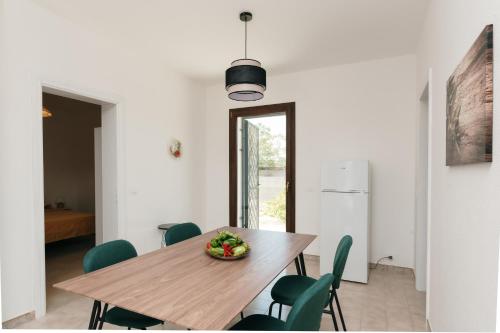 a dining room with a wooden table and green chairs at Villetta L'Ajara - Salento - Ortelle in Ortelle