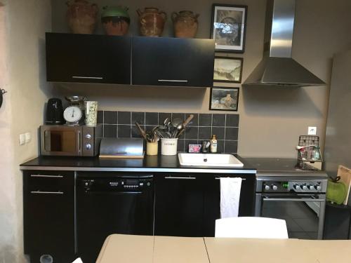 a kitchen with a black counter top and a sink at La maison de Fanny in Jarnioux