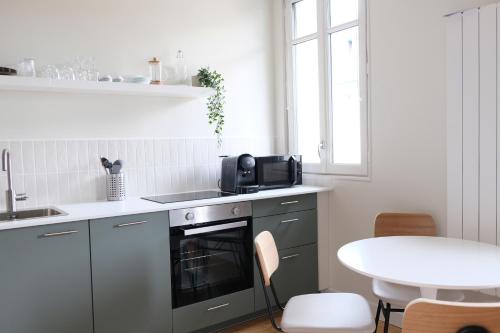 a kitchen with a stove and a sink and a table at Villa Adèle, Sauna et Balcon vue Mer - Appt 03 in Mers-les-Bains