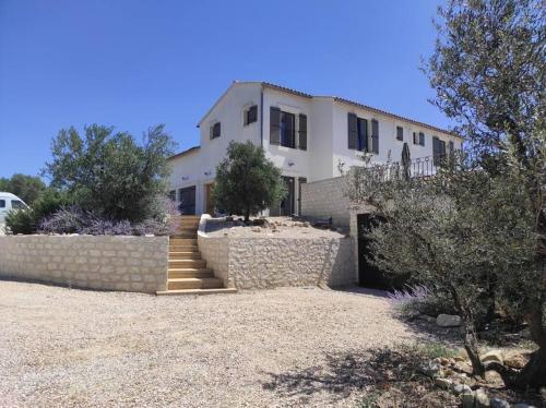 Cette grande maison blanche est dotée d'un mur en pierre. dans l'établissement Magnifique Mas contemporain, à Fontvieille
