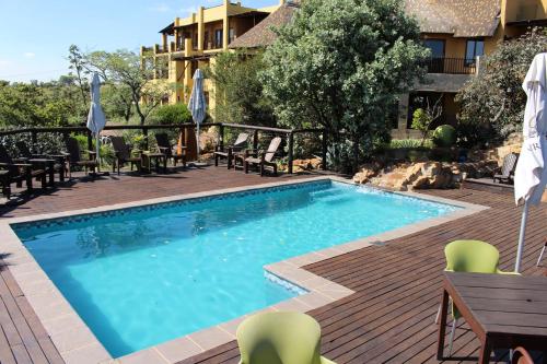 a swimming pool with chairs and a table on a patio at Ndlovu Lodge in Pretoria