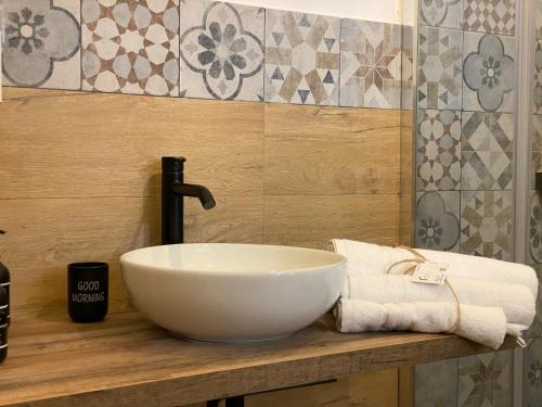 un bagno con lavabo a ciotola e asciugamani su un bancone di CASA NO-MA in centro storico a Marsala