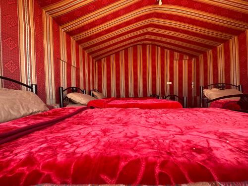 a large red bed in a room with red sheets at Wadirum sunset camp in Wadi Rum