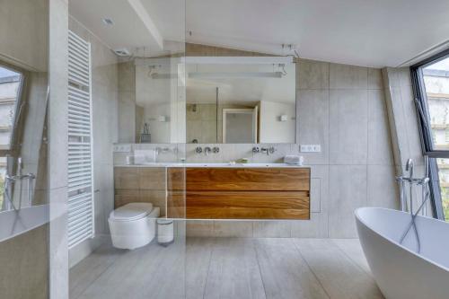 a bathroom with a sink and a toilet and a tub at Luxury Penthouse with A/C Terrace & View-Le Marais in Paris