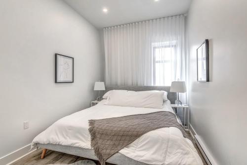 a white bedroom with a bed and a window at Cozy oasis double king size bed: Bell Center - Heart of downtown in Montréal