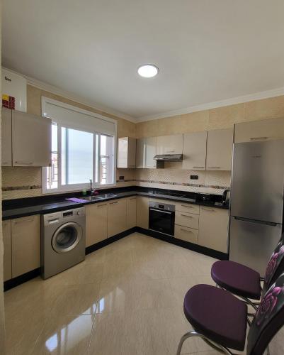 a kitchen with white cabinets and a washer and dryer at Résidence De Luxe AL Manzah in Al Hoceïma