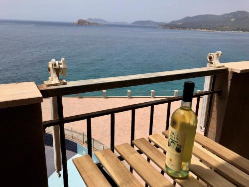 a bottle of wine sitting on a bench overlooking the ocean at orizzonte mare in Teulada
