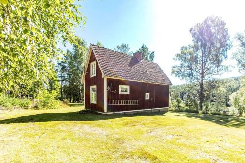 a red barn on a grassy field with trees at Lekvattnet 129 in Torsby