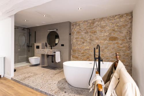 a bathroom with a large tub and a stone wall at Château de Sanse in Sainte-Radegonde