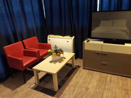 a living room with two chairs and a table and a television at Residence ACHENBACH in Abidjan