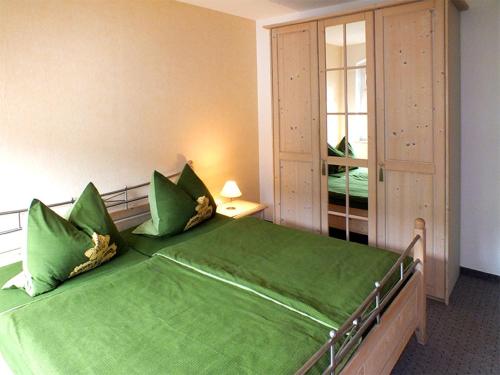 ein grünes Bett in einem Zimmer mit Fenster in der Unterkunft Pension Grenzeck in Bad Schandau