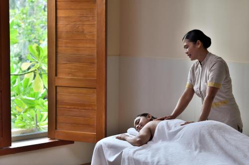 Eine Frau, die neben einem Patienten in einem Bett steht. in der Unterkunft Sheraton Kosgoda Turtle Beach Resort in Bentota