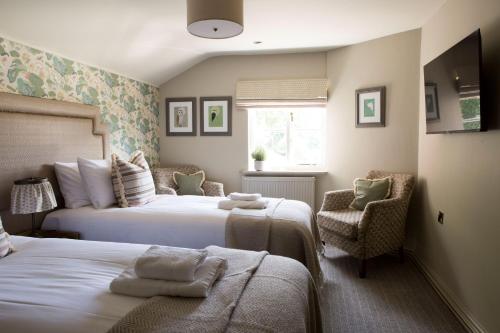 a bedroom with two beds and a chair at Alvanley Arms, Cotebrook in Tarporley