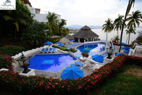 una piscina con sillas y sombrillas azules en Departamento junto a las hadas manzanillo en Manzanillo