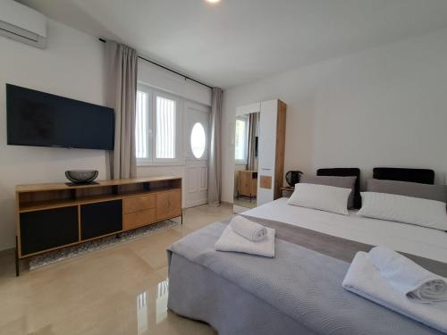 een slaapkamer met een groot bed en een flatscreen-tv bij Studio apartment SeaDream - 50 meters from the sea in Brodarica