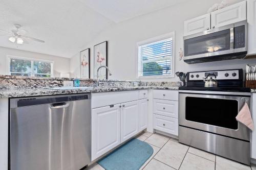a kitchen with white cabinets and stainless steel appliances at Beachy 2-1 Condo in Palm Harbor