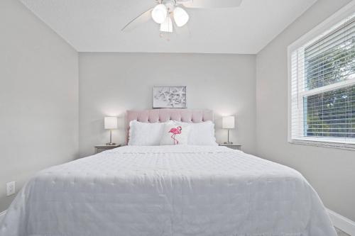 a white bedroom with a large white bed with a pink headboard at Beachy 2-1 Condo in Palm Harbor