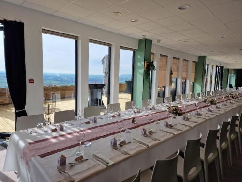 einen langen Tisch in einem Zimmer mit Stühlen und Fenstern in der Unterkunft Auberge du Fort Pélissier in Pont-Saint-Vincent