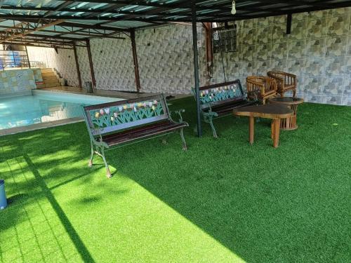 two benches sitting on grass next to a swimming pool at Villa Bukit Punclut in Bandung