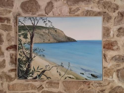 a painting of a beach with a tree on a wall at Το Πέτρινο in Aitolikón