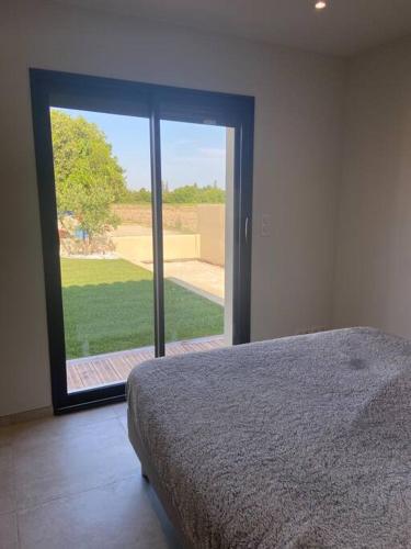 - une chambre avec un lit et une grande porte en verre dans l'établissement Le nid d'Emilie, à Maillane