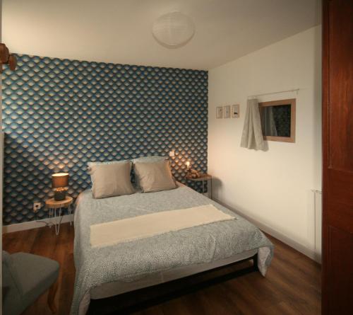 a bedroom with a bed with a blue and white patterned wall at Les appartements de Clélia in Ax-les-Thermes