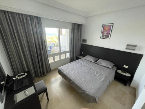 a hotel room with a bed and a window at Beachfront Apartment - Andalucia in Bizerte